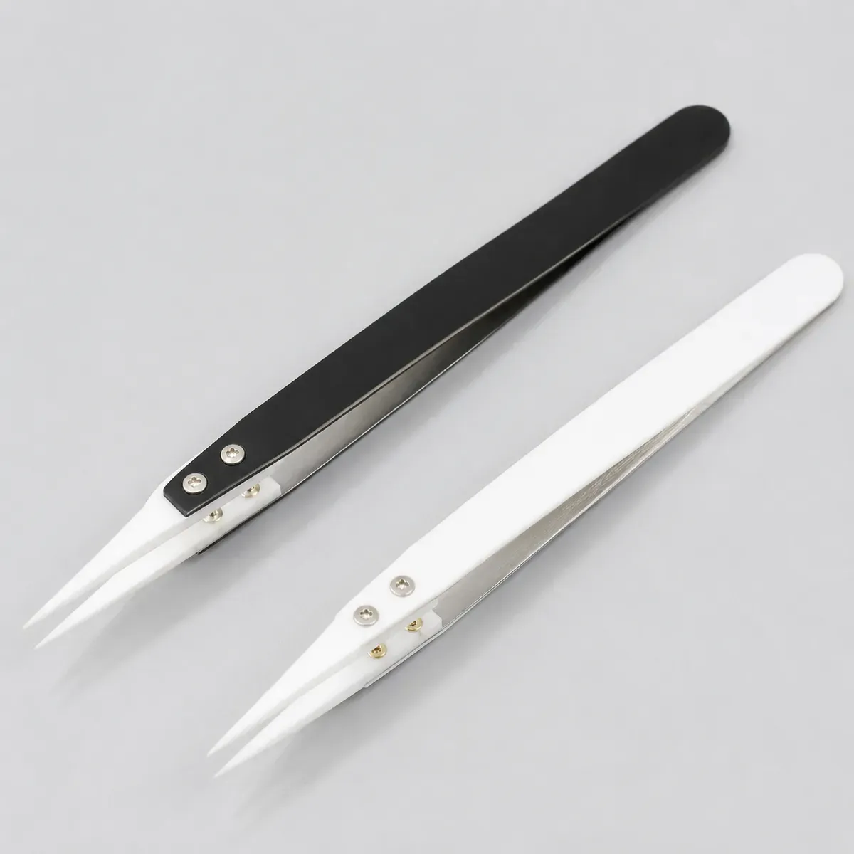 Ceramic precision tweezer set with black and white handles on light gray background