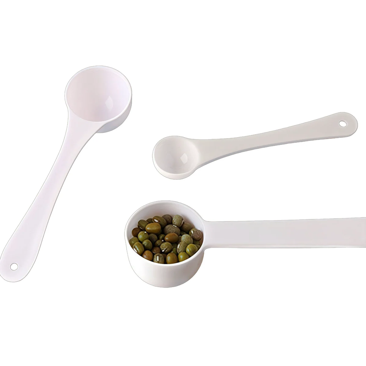 Three plastic dosing spoons with dry granules in the largest bowl